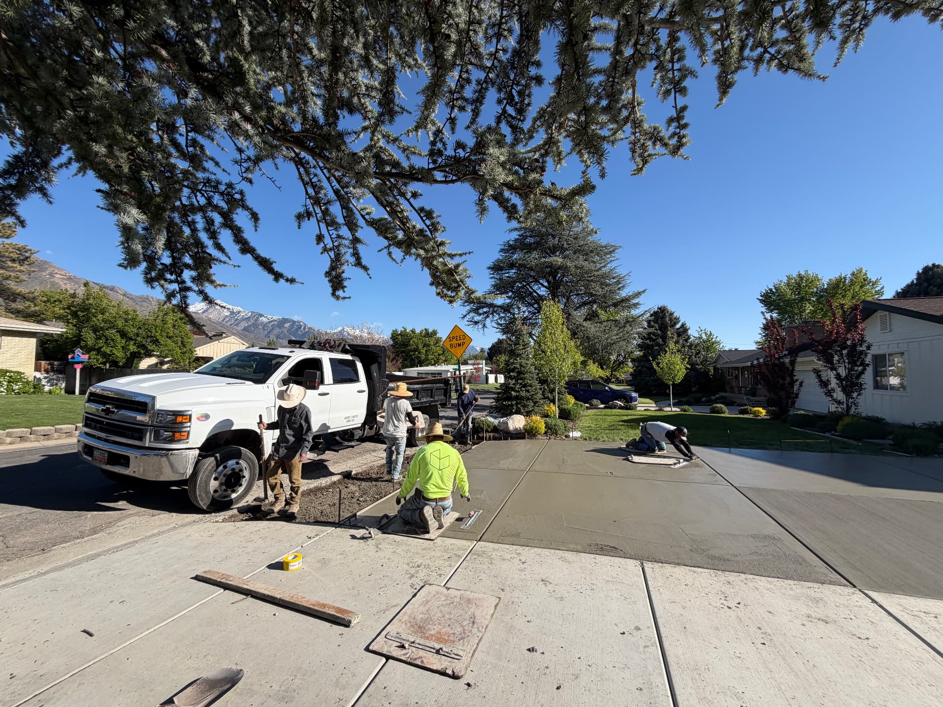 Crew finishing a freshly poured residential driveway with the mountains behind